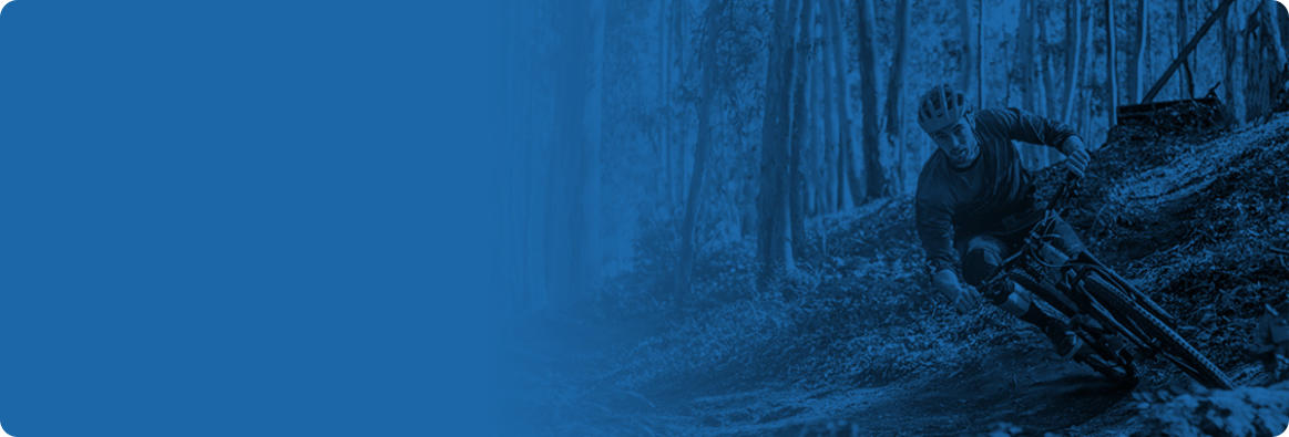 Image of man riding a bike through a wooded trail